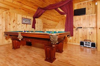 The pool table is in an upstiars loft. The room has wood floors, wood ceiling, and wood walls. It is a true log cabin.